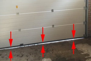 Arrows pointing to the space between the garage door and floor showing how to measure the gap