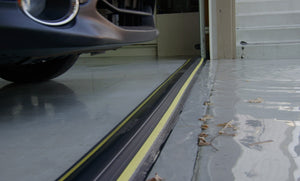 A garage protected by the 50mm garage door flood barrier Garadam with leaves and rain outside it